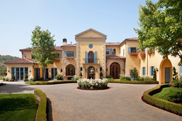 this tuscan inspired yellow house with blue shutters features a spacious driveway