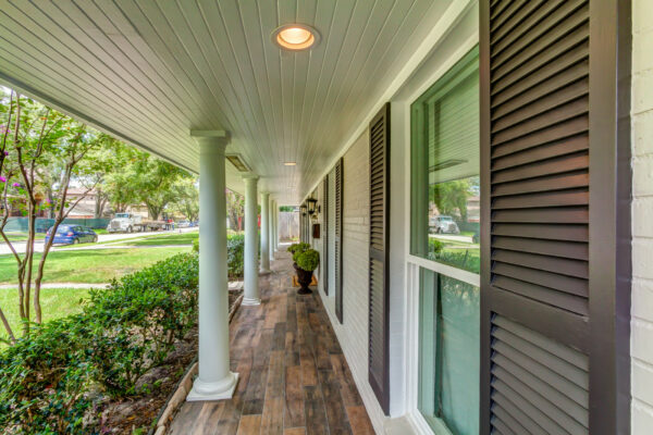 a long and narrow front porch looks elegant with wood tile and painted brick walls