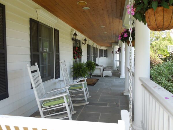 add classic rocking chairs on a front porch with bluestone tile and wood ceilings
