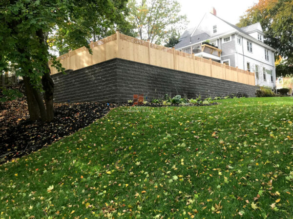 consider a grand atmosphere with a cedar tongue fence on allan block’s ab classic stone retaining wall