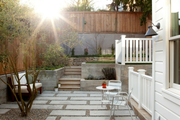 create a contemporary patio featuring classic white fence on concrete retaining wall
