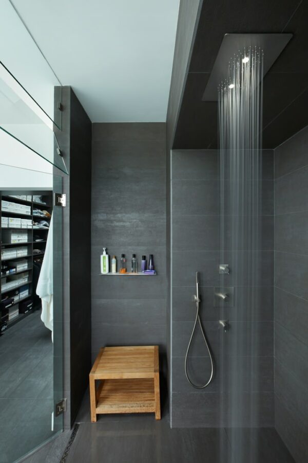 embrace a modern interior with a sleek rain head and shower shelf in a dark grey bathroom