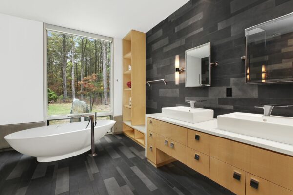 go for a dramatic freestanding bathtub design to elevate a dark grey bathroom with basalt tiles and wood furnishing