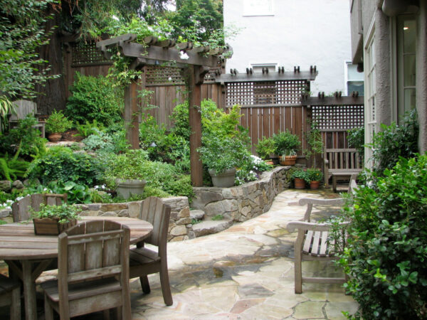 pair trellis and fence on a low stone retaining wall for added seclusion with relaxing, lush plantings