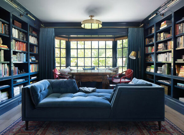 the bay window and floor-to-ceiling bookshelves are perfect for a large and cozy navy blue office