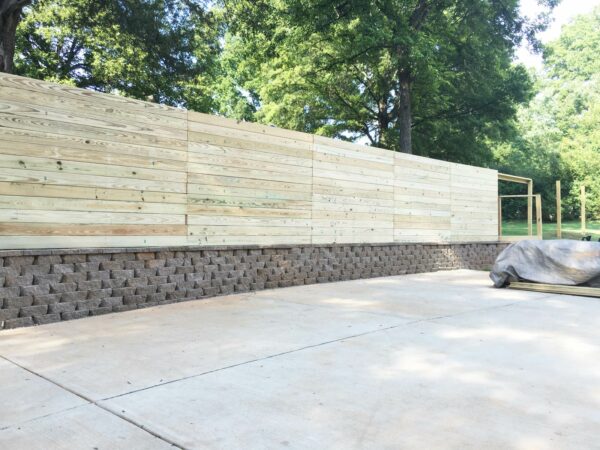 this horizontal fence on the retaining wall provides full privacy and shade in a full sun yard