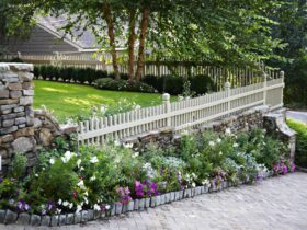 try a short picket fence on a retaining wall made of moss rock stones for privacy without blocking the view