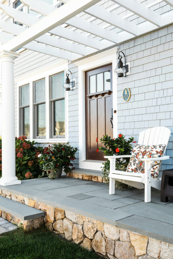 build a coastal-inspired exterior with a white front door pergola and onion lights in muted colors