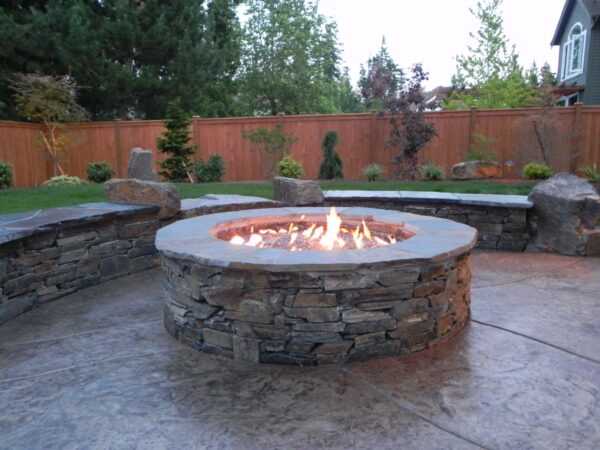 combine flagstone border with stamped concrete patio to complement a traditional round fire pit