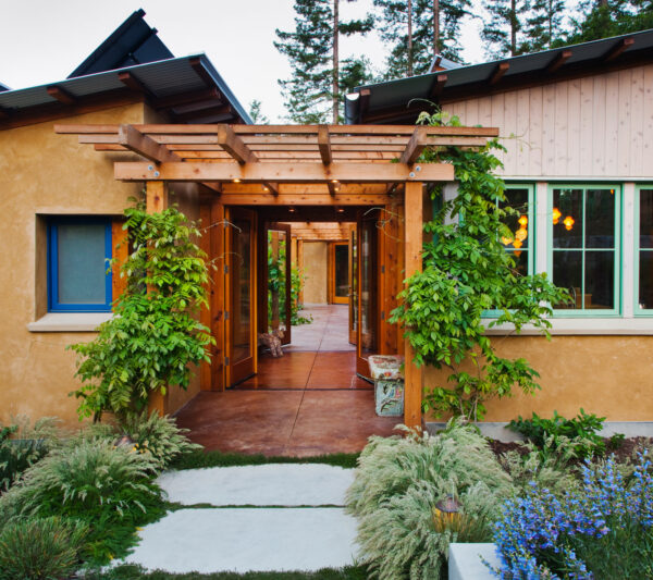 contrast concrete flooring with roof overhangs and deciduous vines on a front door pergola for a relaxing atmosphere