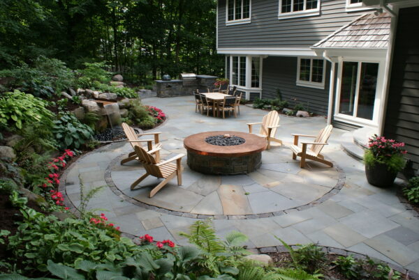 go for a large and spacious feel using an irregular bluestone patio and a copper fire table