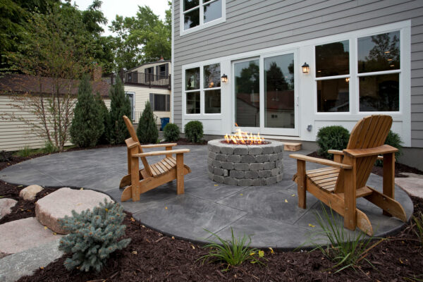 place wooden adirondack chairs on a stamped concrete patio with a fire pit for a traditional and timeless appeal