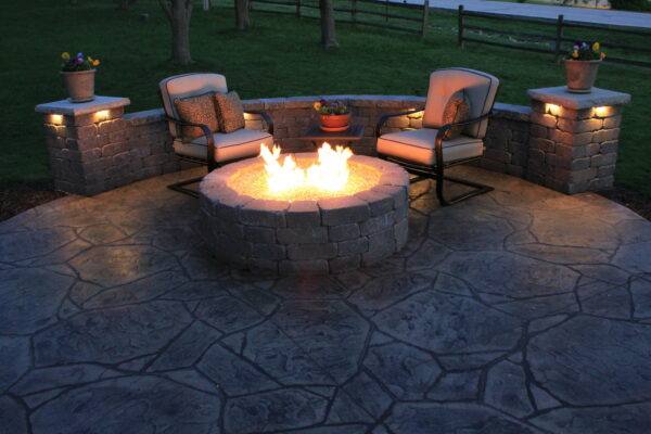 this flagstone stamped concrete patio looks striking under a fire pit with fire glass and a belgard weston seat wall