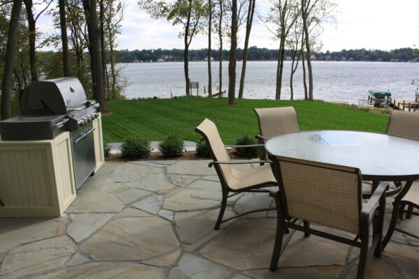 this irregular new york bluestone patio features an outdoor bbq and dining set for a scenic area