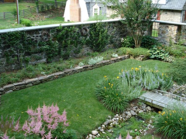 build an idyllic backyard stone wall for a lush garden featuring crape myrtles and other plantings