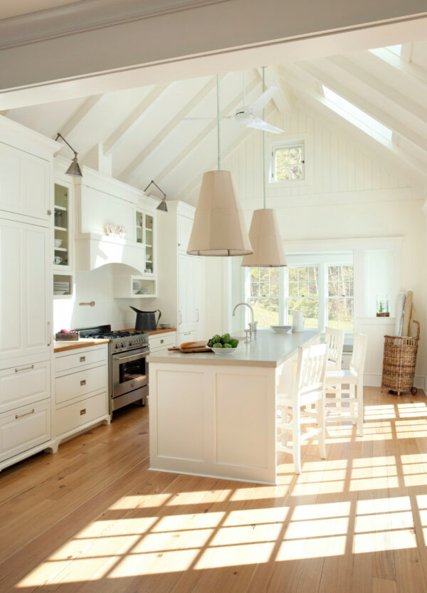 this bright farmhouse galley kitchen with an island features linen pendants for a homey feel