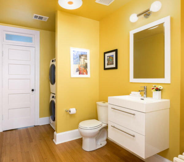 this bright yellow laundry and powder room use a false wall to keep it clutter-free