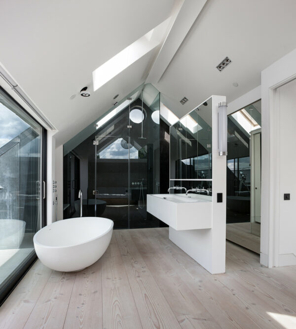 this trendy white bathroom features a false mirror wall and light wood flooring