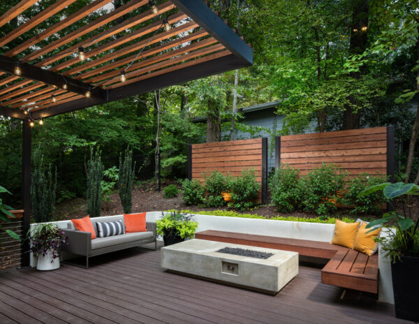 use cedar screens as a backyard wall to ensure privacy and style while adding a concrete fire table and floating bench